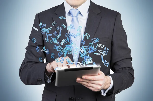 Businessman is searching something in internet using a tablet. Flying social media icons. — Stock fotografie