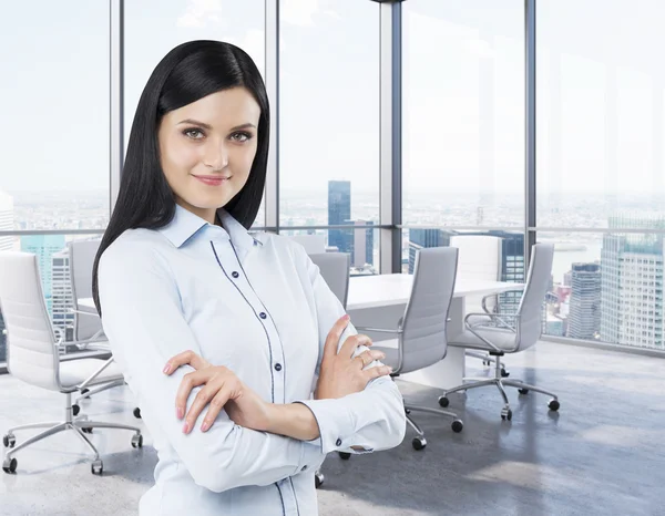 Bella bruna in una sala conferenze ad angolo. Ufficio moderno con grandi finestre e splendida vista panoramica su New York . — Foto Stock