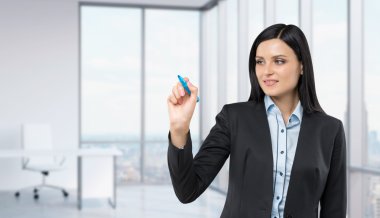 Beautiful woman drawing on a glass board. Panoramic corner office on background.