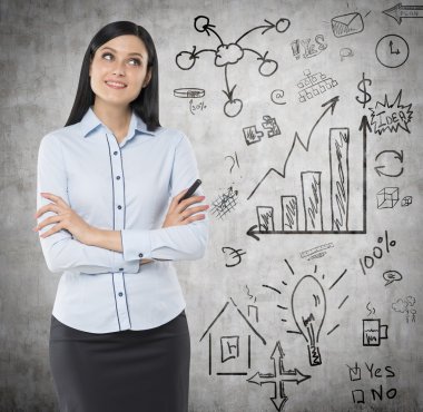 Front view of a thoughtful woman with crossed hands. A concept of a brainstorm. Business icons are drawn on the wall. Concrete background.