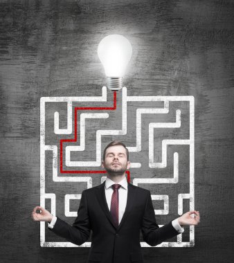 Meditative businessman and solved labyrinth with a light bulb on the black chalk board. clipart