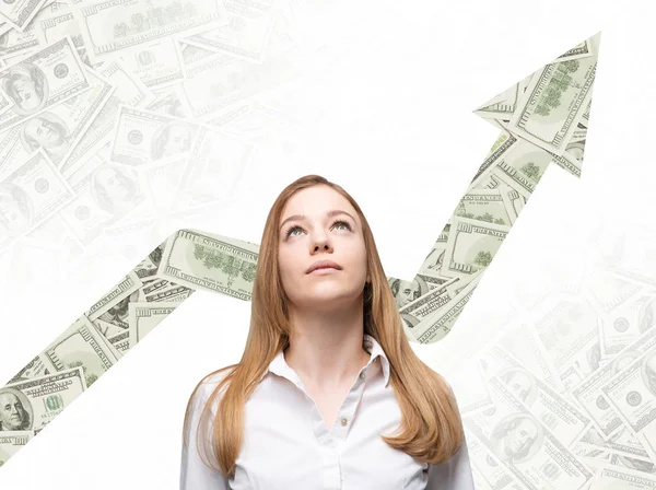 Uma mulher de negócios está olhando para cima e pensando em como aumentar o retorno do processo de negócios. Flecha crescente que é feita de notas de dólar no fundo . — Fotografia de Stock
