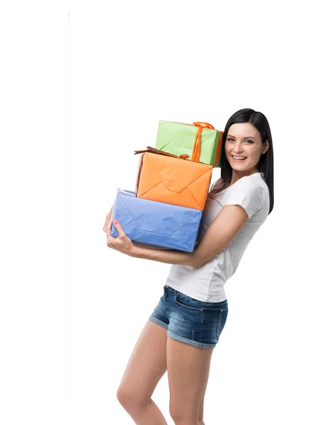 Una mujer morena sostiene tres coloridas cajas de regalo. Aislado . — Foto de Stock