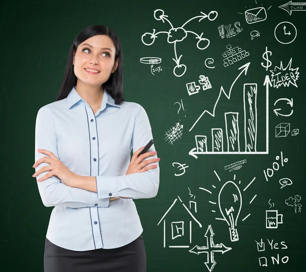 Front view of a thoughtful woman with crossed hands. A concept of a brainstorm. Business icons are drawn on the green chalk board. — Stockfoto