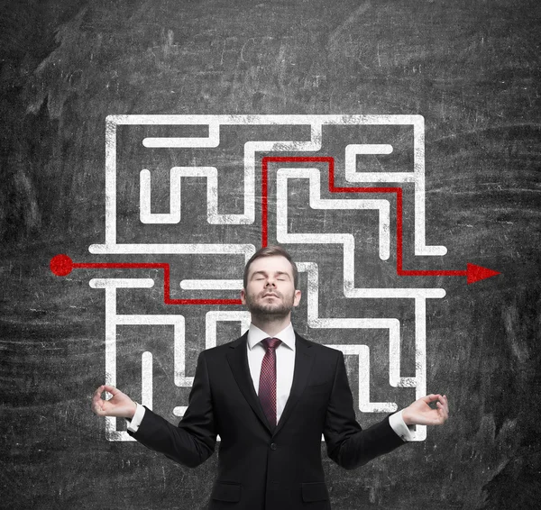 Meditative businessman and solved labyrinth with a red arrow on the black chalk board. — Stockfoto