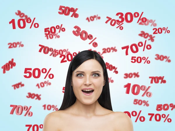 Astonished brunette surrounded by discount and sale numbers: 10% 20% 30% 50% 70%. Blue background. — Stock Photo, Image