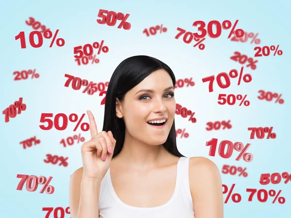 Astonished brunette surrounded by discount and sale numbers: 10% 20% 30% 50% 70%. Blue background. — Stok fotoğraf