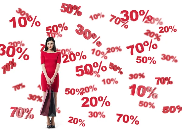 Happy brunette in a red dress with the shopping bags. Discount and sale symbols: 10% 20% 30% 50% 70%. Isolated. — Stock Photo, Image