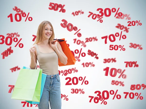 Happy brunette with the colourful bags. Discount and sale symbols: 10% 20% 30% 50% 70%. Blue background. — Stock Photo, Image