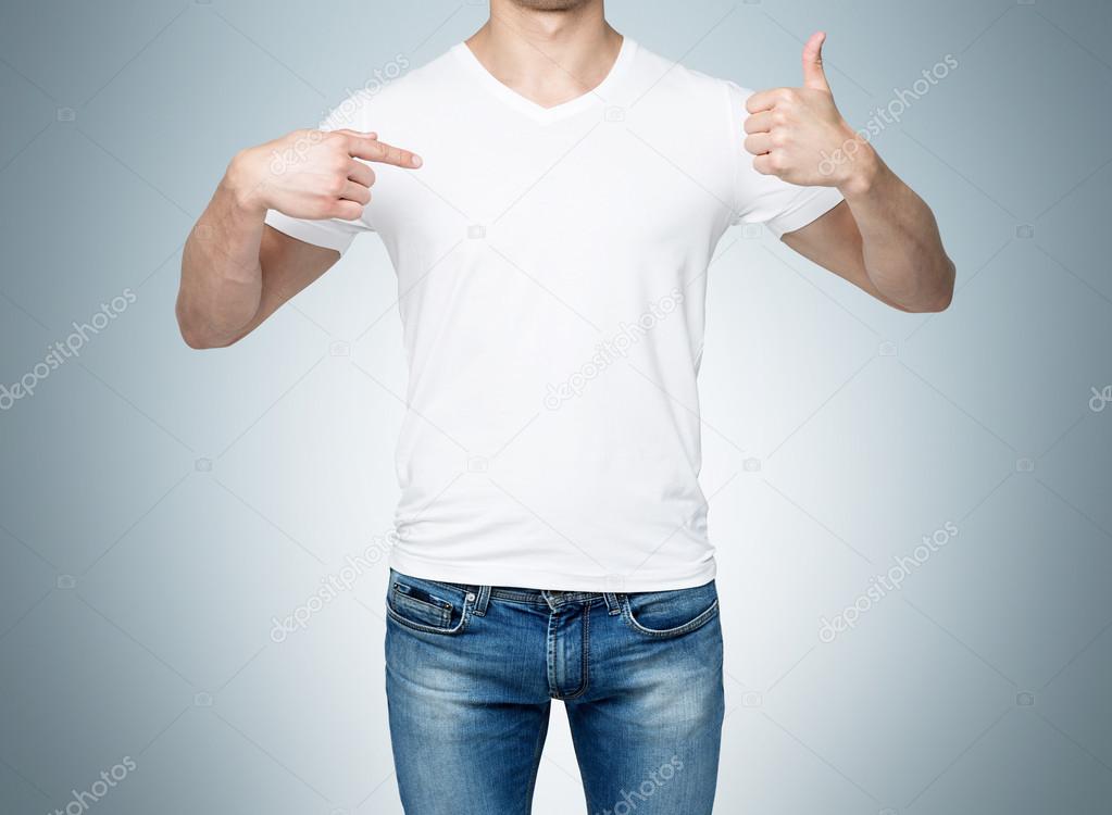 Close-up of a man pointing his finger to a blank t-shirt, and the thumb up. Blue background.