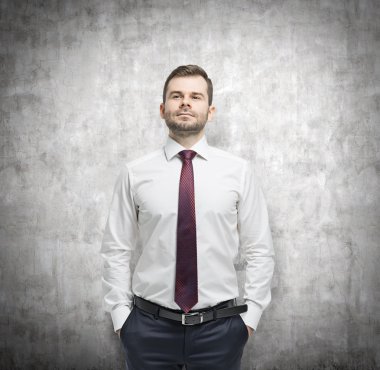 Kendine güvenen işadamı elleri ceplerinde. Beton arka plan.