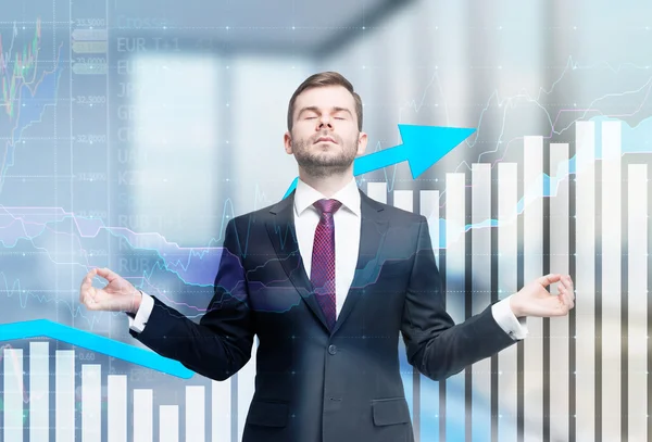 Meditative businessman is looking for the perfect business solution. Financial charts and office view in blur on the background. — Stock Photo, Image