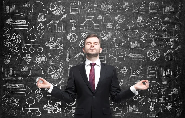 Meditative businessman is looking for the best solution for the business development process. Business icons are drawn over the huge blackboard. — Stock Photo, Image