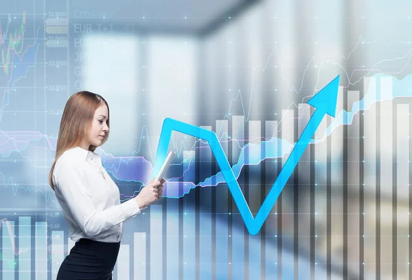 Young thoughtful lady is searching something in the internet using the tablet. Financial charts and office view in blur on the background. — 图库照片