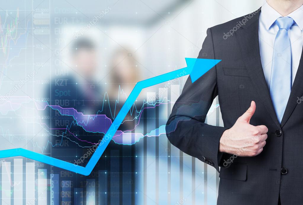 Businessman thumb up and growing arrow. Financial charts and business couple in blur on the background.