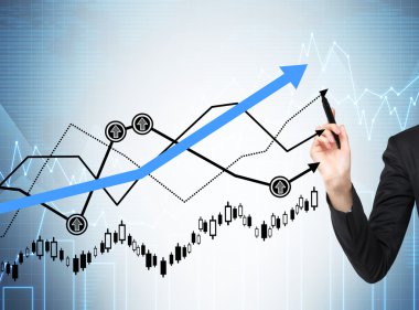 Woman's hand is drawing a growing graphs. Forex chart on the background.