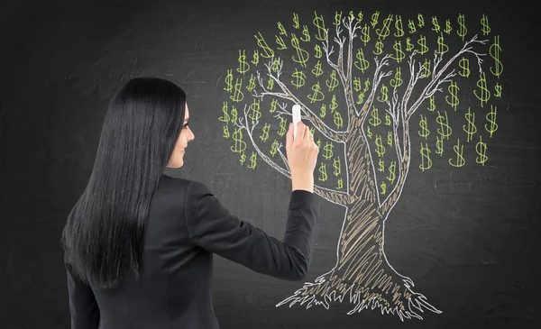 Brunette business woman is drawing a tree on the chalk blackboard. — Stock Fotó