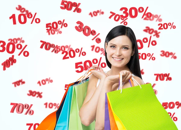 Una joven feliz con las coloridas bolsas de compras de las tiendas de lujo. Signos de descuento están volando sobre el fondo blanco . — Foto de Stock