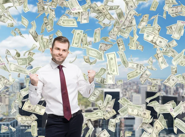 Closeup portrait of happy successful businessman who close the deal, fists pumped. A concept of celebrating the success. Dollar note are falling down over the business city. — Stock fotografie