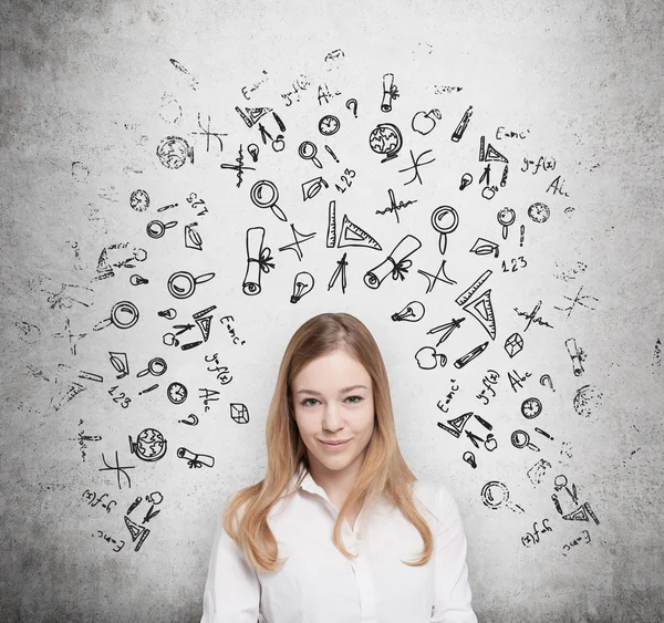 Young beautiful student is thinking about education at business school. Drawn business icons over the concrete wall. — Stockfoto