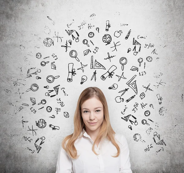 Young beautiful student is thinking about education at business school. Drawn business icons over the concrete wall. — Φωτογραφία Αρχείου