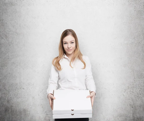 Business woman holds a couple of pizza's boxes. Concrete wall as a background. — Zdjęcie stockowe