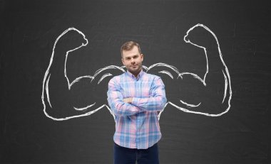 Young handsome man in casual shirt with drawn powerful hands. Black chalkboard background. clipart