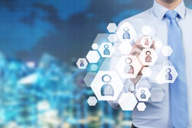 A concept of recruitment process. A hand is choosing the right icon as a concept of the right candidate. City view in blur as a background.