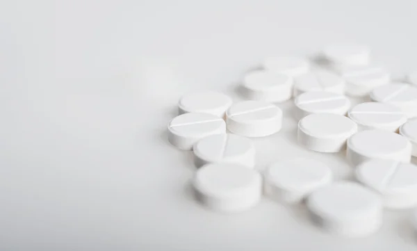 Píldoras blancas derramadas en la superficie blanca — Foto de Stock