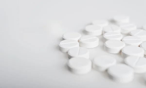 Spilled white pills on the white surface — 图库照片