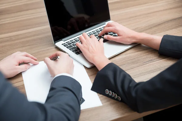 Business colleagues are working on the project. A laptop and a blank paper are on the table. Toning filter. — Zdjęcie stockowe