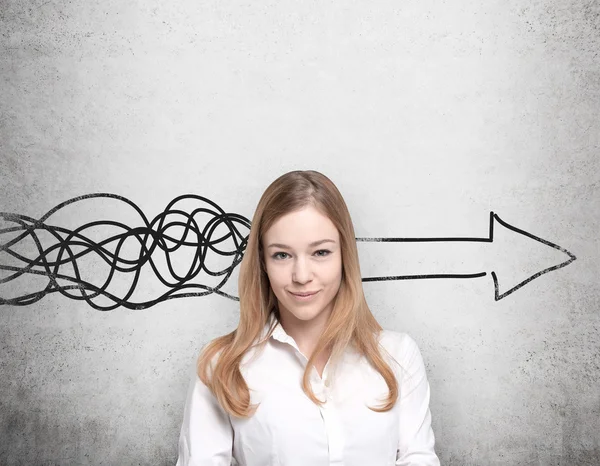 Beautiful young woman is thinking about concept of business development. A huge arrow are drawn on the concrete wall. — Stock Photo, Image