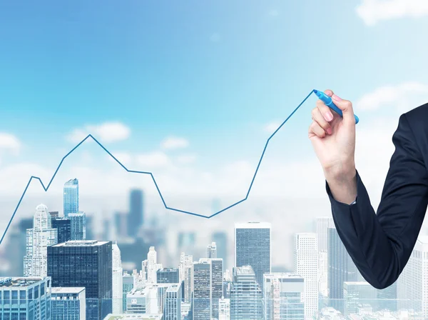 A hand is drawing a growing line graph on the glass screen. New York City space on the background. — Stock Photo, Image