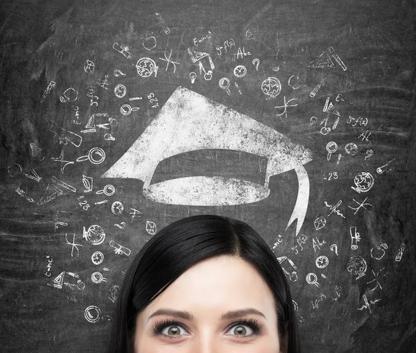 Een hoofd van de jonge brunette dame die denkt over universitair onderwijs. Getekende educatieve iconen en een afstuderen hoed op de zwarte schoolbord achtergrond . — Stockfoto