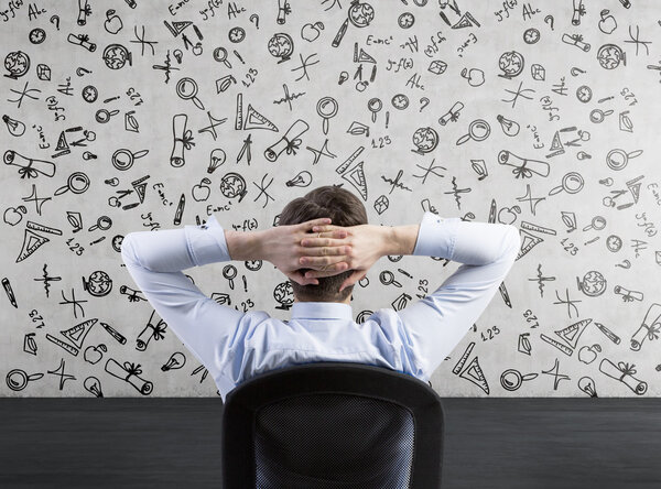 Rear view of the relaxing businessman who thinks about further education. Concrete background.