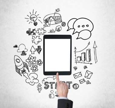A tablet, digital device with copy space screen is surrounded by drawn business icons. A hand is pushing the button. Concrete background.