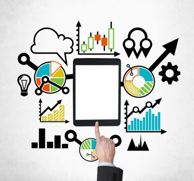 A tablet, digital device with copy space screen is surrounded by drawn colourful business icons. A hand is pushing the button. Concrete background.