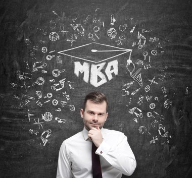 Genç yakışıklı profesyonel işletme mastırını düşünüyor. Mezuniyet şapkası ve beton zemine eğitim simgeleri çizdim. .