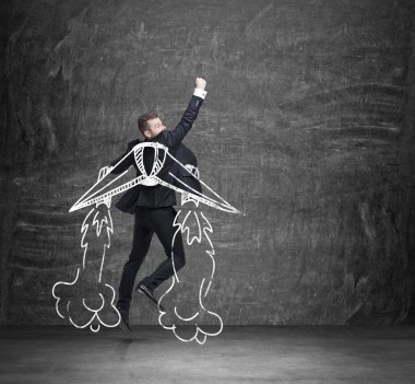 A concept of business angel. A businessman is flying over the black chalkboard.