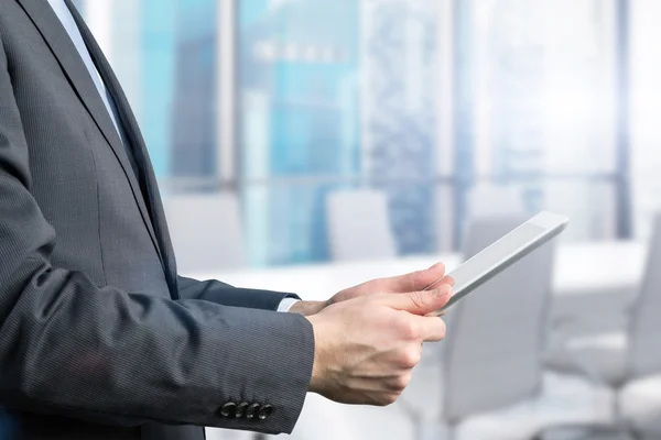 Close-up of side view of a businessman who is browsing on his tablet. Office view with Singapore panoramic view. — Stockfoto