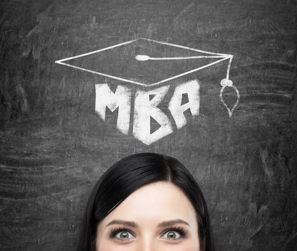 Une tête de jeune femme brune qui pense à un diplôme de MBA. Dessiné un chapeau de graduation sur le fond de tableau noir  . — Photo