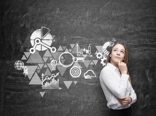 Joven mujer de negocios está pensando en el esquema de optimización de negocios. pizarra de tiza negra como una pared en el fondo . —  Fotos de Stock