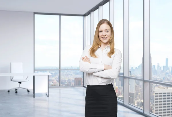 Bonito empregado sorridente está de pé no escritório com vista panorâmica de Nova York. Um conceito do local de trabalho moderno . — Fotografia de Stock