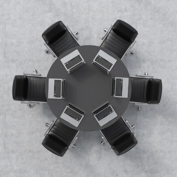 Top view of a conference room. A black round table, six leather chairs and six laptops. Office interior. 3D rendering. — Stock fotografie