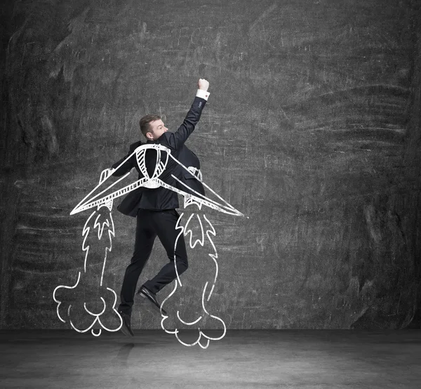 A concept of business angel. A businessman is flying over the black chalkboard. — Stock Photo, Image