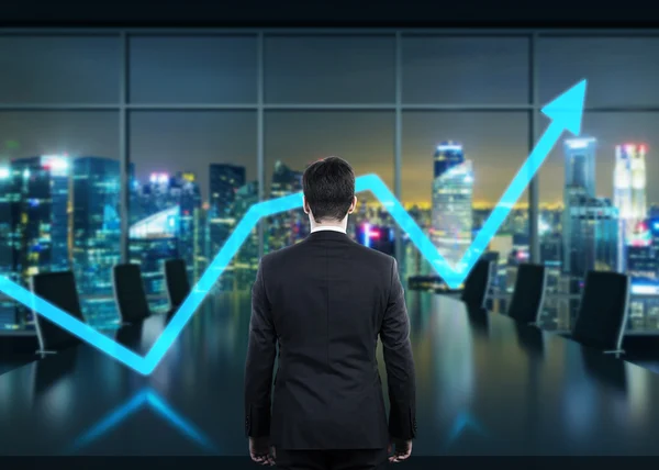 Rear view of the businessman in the office at night time. Rising arrow as a symbol of the success. — Stock Photo, Image