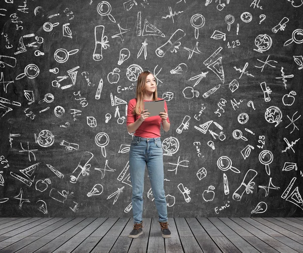 Young lady is pondering about education. Educational icons are drawn on the black chalk wall. — 스톡 사진