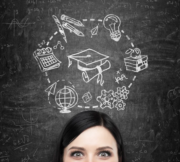 Eine Stirn der brünetten Dame, die über Studium und Abschluss nachdenkt. Bildungsikonen werden auf die schwarze Tafel gezeichnet. — Stockfoto