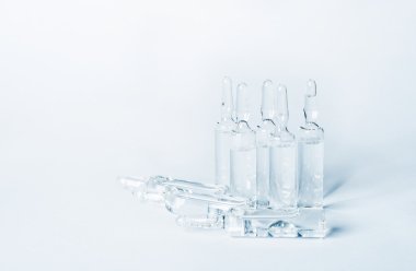 Break-seal glass ampoule set with liquid medicine on light blue background.
