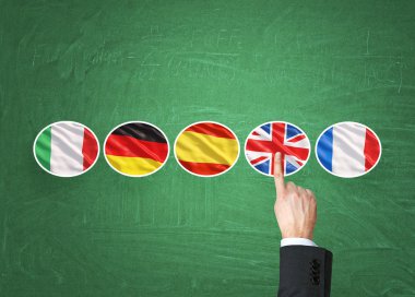 A concept of foreign language studying process. A finger is pointing out the Unites Kingdom flag as a priority in choice of foreign languages. Green chalkboard background.